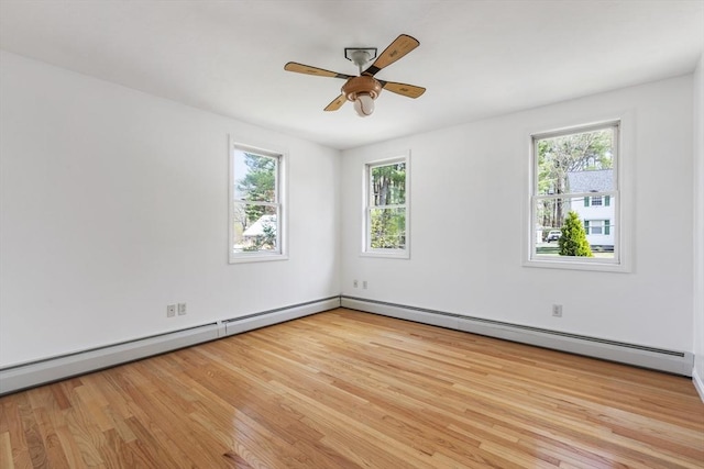 empty room featuring ceiling fan, baseboard heating, light wood-style flooring, and a wealth of natural light