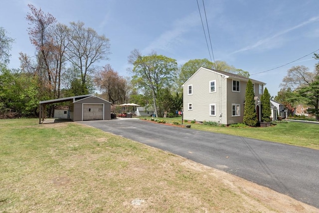 view of property exterior featuring a lawn, an outdoor structure, a garage, and aphalt driveway