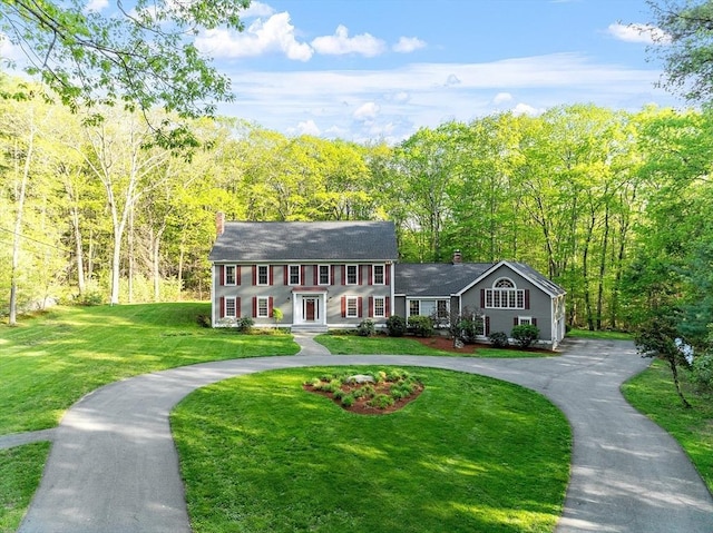 132 Ember, Carlisle, MA 01741 - colonial house featuring a chimney, curved driveway, a front lawn, and a wooded view