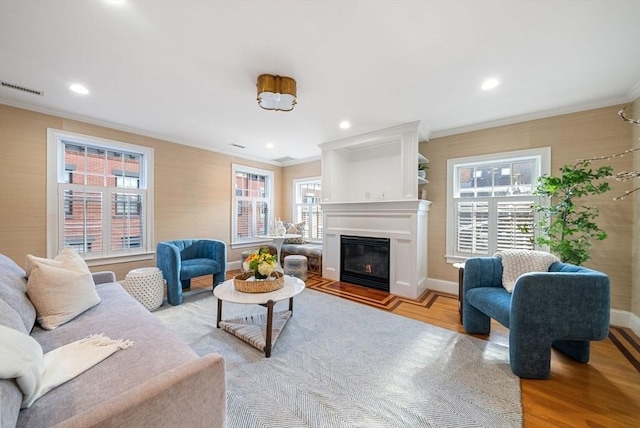 living room with crown molding, plenty of natural light, and light hardwood / wood-style flooring