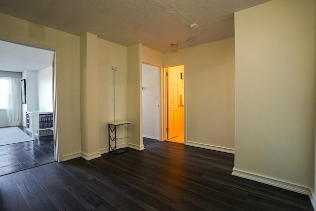 spare room featuring dark hardwood / wood-style flooring and a textured ceiling