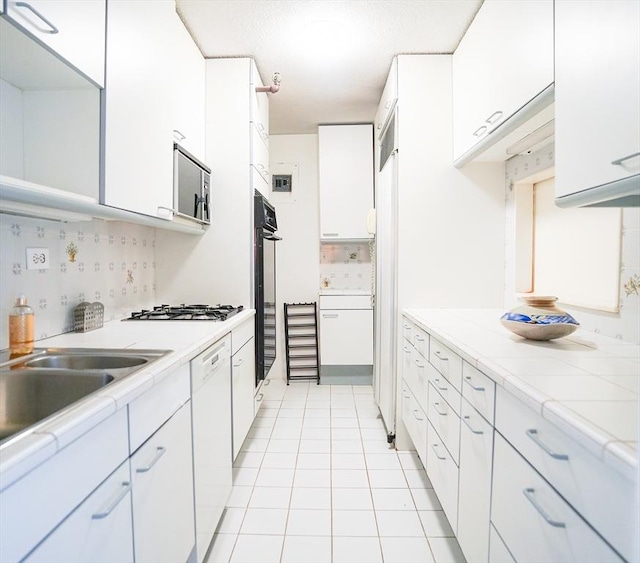 kitchen featuring white cabinets, stainless steel appliances, and light tile patterned floors