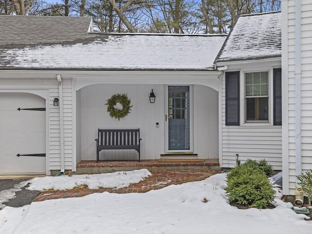 snow covered property entrance with a garage