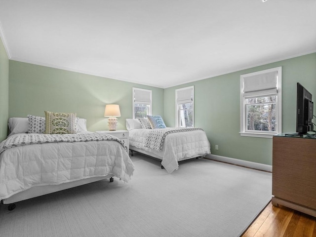 bedroom featuring crown molding, wood-type flooring, and multiple windows