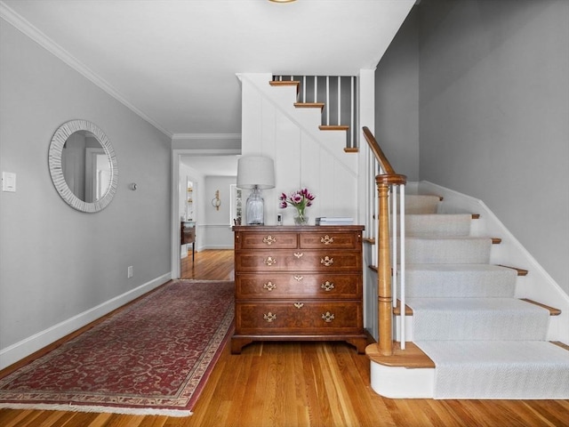 staircase with wood-type flooring and ornamental molding