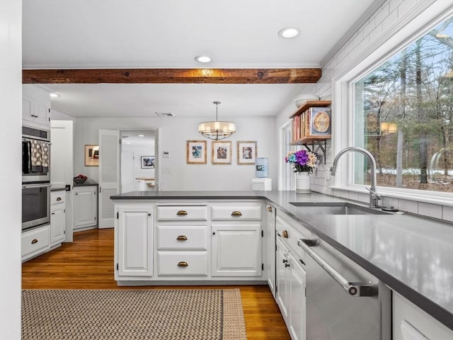 kitchen featuring sink, appliances with stainless steel finishes, white cabinets, decorative light fixtures, and kitchen peninsula