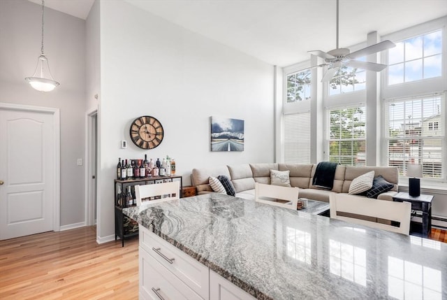 743 E 4th Unit 204, Boston, MA 02127 - kitchen featuring a towering ceiling, light stone countertops, a ceiling fan, light wood-type flooring, and white cabinetry