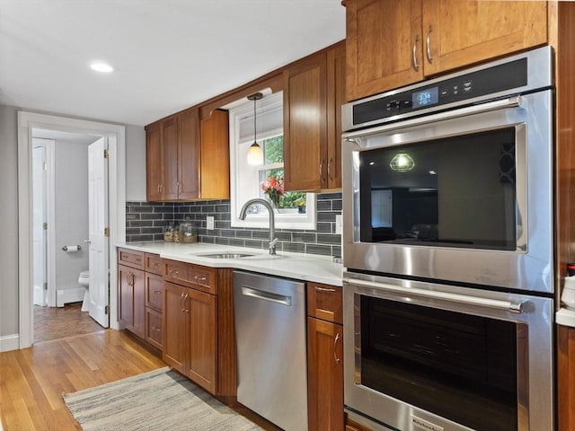 886 Methuen St, Dracut, MA 01826 - kitchen featuring stainless steel appliances, light countertops, light wood-style floors, and brown cabinetry