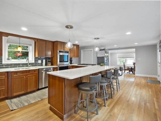 886 Methuen St, Dracut, MA 01826 - kitchen featuring appliances with stainless steel finishes, light wood-type flooring, light countertops, brown cabinets, and recessed lighting