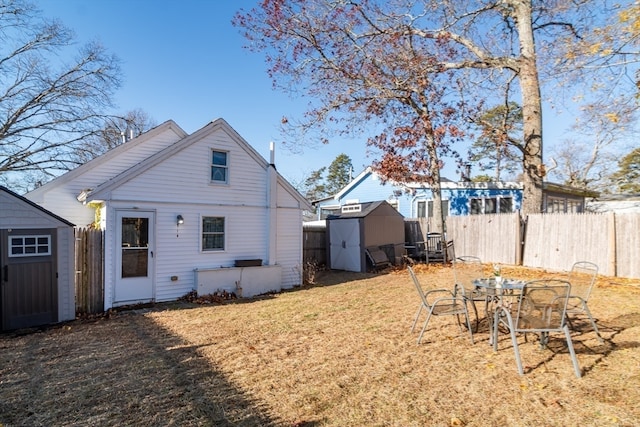 rear view of property with a lawn and a storage unit