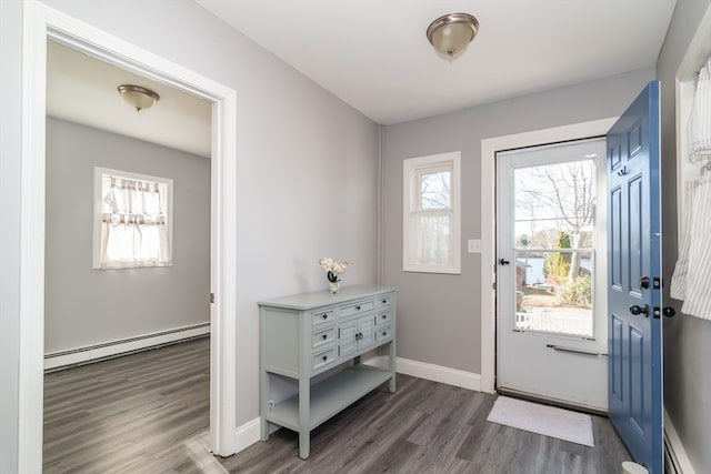 foyer with a wealth of natural light, baseboard heating, and dark wood-type flooring