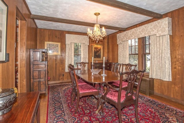 dining space with hardwood / wood-style flooring, wood walls, a textured ceiling, a chandelier, and beam ceiling