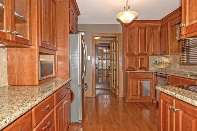 kitchen with backsplash, pendant lighting, light hardwood / wood-style flooring, stainless steel appliances, and light stone counters