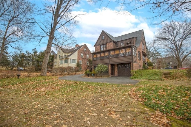 back of property featuring a garage, a sunroom, and a yard