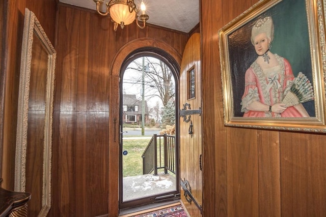 foyer featuring wooden walls and a chandelier