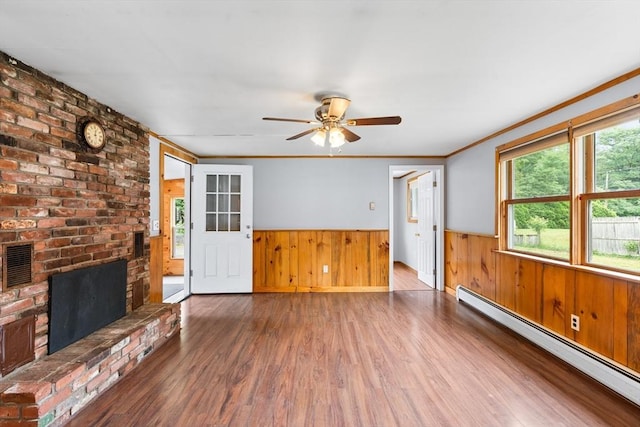 24 Horton Rd, Orange, MA 01364 - unfurnished living room featuring baseboard heating, a wainscoted wall, wood finished floors, wood walls, and ceiling fan
