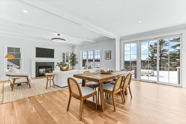 dining space featuring crown molding, light wood-type flooring, and beam ceiling