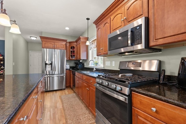 1 Windsor Rd, Shirley, MA 01464 - kitchen featuring appliances with stainless steel finishes, light wood-type flooring, brown cabinets, hanging light fixtures, and dark stone counters