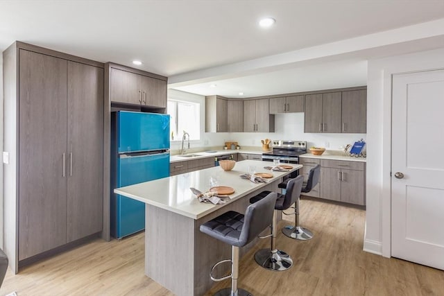 247 Pitman St, Fall River, MA 02723 - kitchen with appliances with stainless steel finishes, a sink, a breakfast bar area, light wood-type flooring, and light countertops