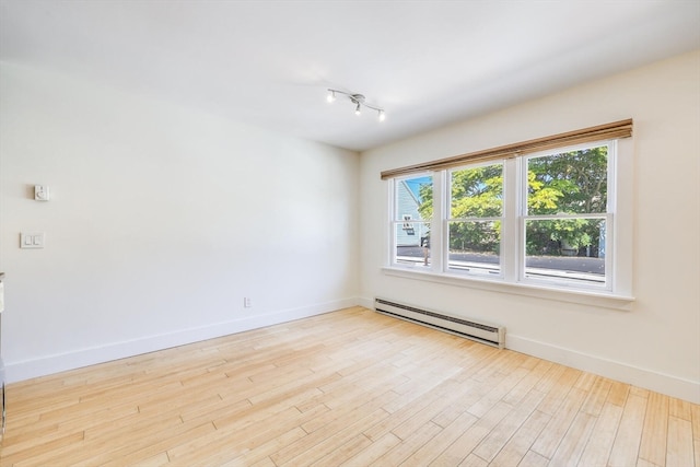 spare room with baseboard heating and light hardwood / wood-style floors