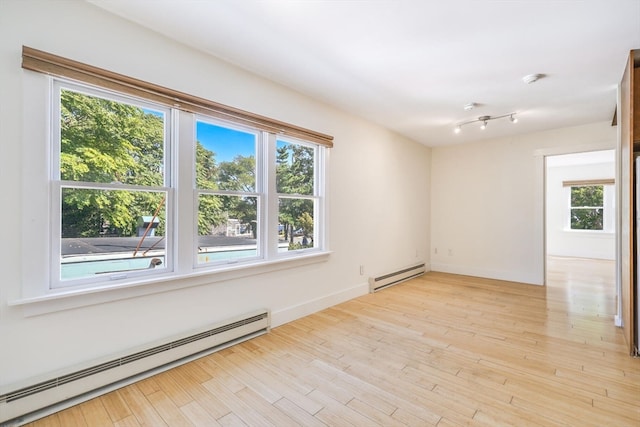 empty room featuring a baseboard heating unit and a wealth of natural light