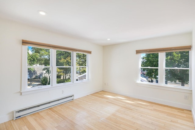 unfurnished room featuring baseboard heating and light wood-type flooring