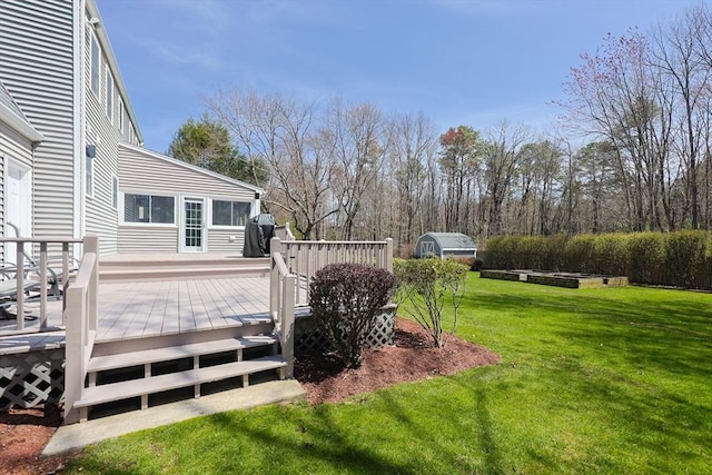 wooden deck featuring an outbuilding, a shed, and a yard