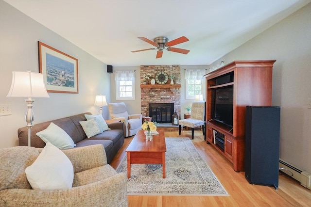 living area with a brick fireplace, ceiling fan, a baseboard radiator, and light wood-style floors