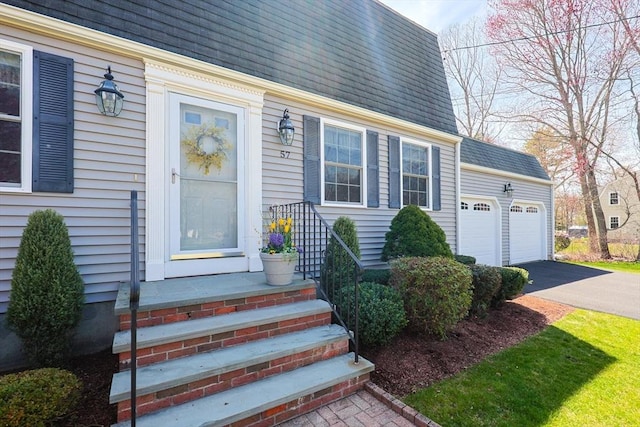 property entrance with driveway and a shingled roof