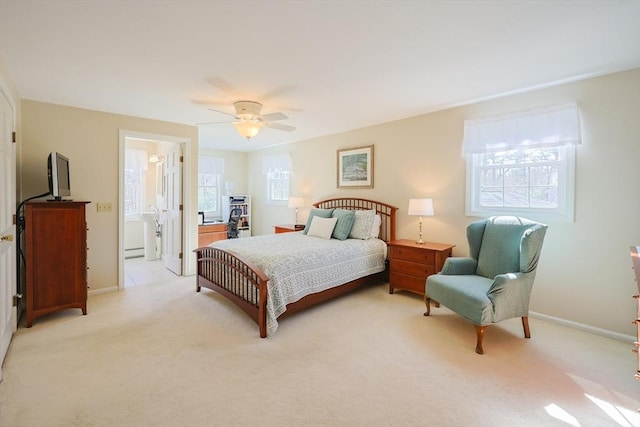 bedroom featuring light carpet, baseboard heating, a ceiling fan, baseboards, and ensuite bathroom