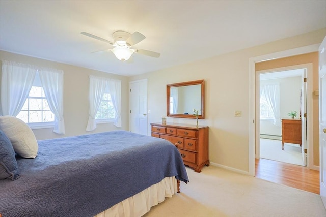 bedroom with baseboards, a ceiling fan, a baseboard heating unit, and light carpet