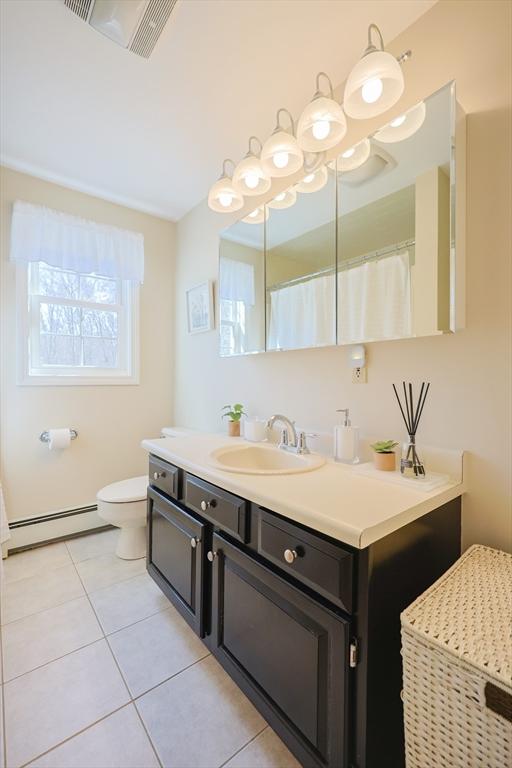 bathroom with visible vents, tile patterned flooring, baseboard heating, vanity, and toilet