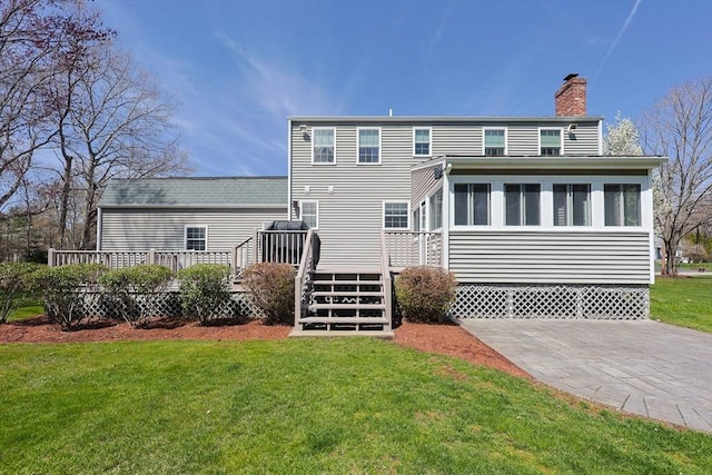 back of house featuring a wooden deck, a chimney, and a yard