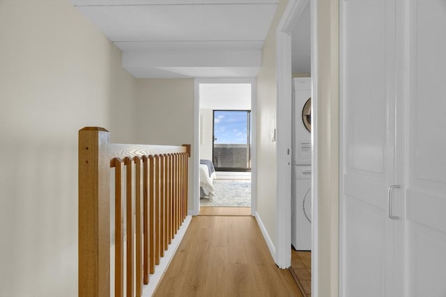 hallway with stacked washer / drying machine and light hardwood / wood-style flooring