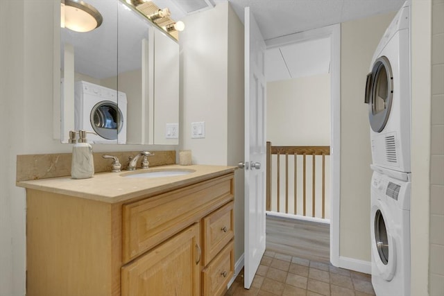 bathroom with tile patterned floors, stacked washer / drying machine, and vanity