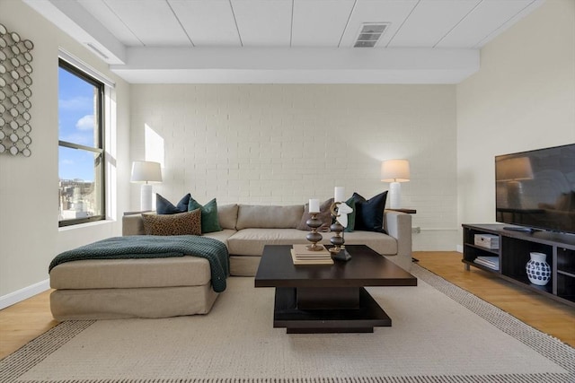 living room featuring brick wall and hardwood / wood-style floors