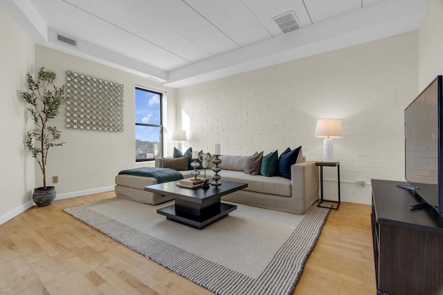 living room featuring brick wall and light wood-type flooring