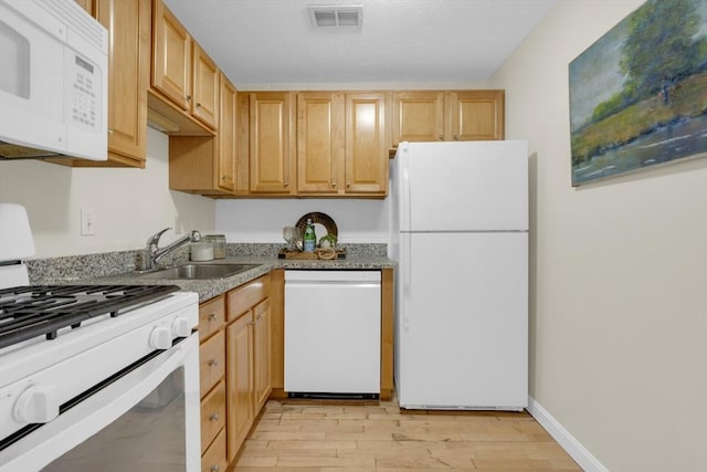 kitchen with sink, white appliances, light brown cabinetry, and light hardwood / wood-style floors