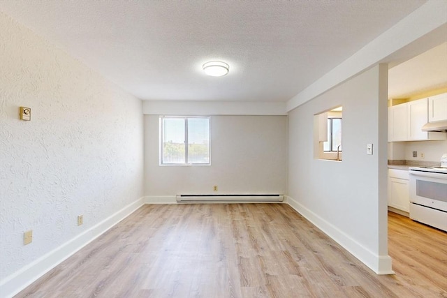 47 Mystic St Unit 4E, Arlington, MA 02474 - spare room featuring a baseboard radiator, light wood-type flooring, a textured wall, baseboards, and a textured ceiling