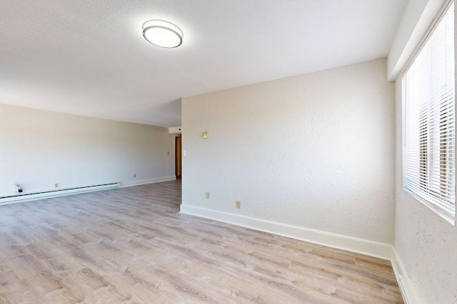 47 Mystic St Unit 4E, Arlington, MA 02474 - spare room featuring a baseboard heating unit, plenty of natural light, light wood-style floors, a textured wall, and baseboards