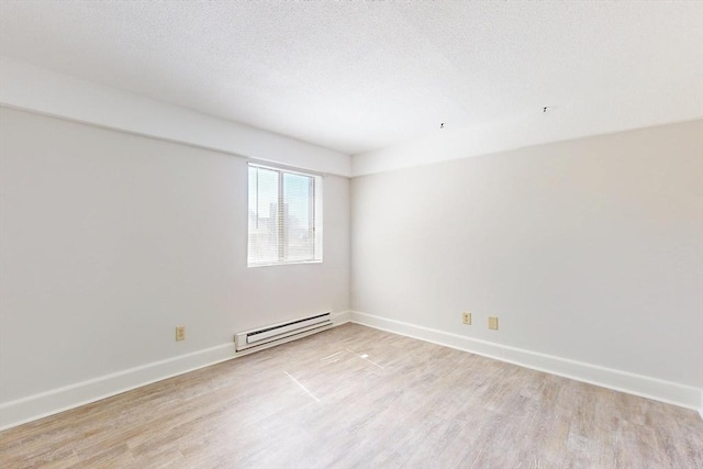 47 Mystic St Unit 4E, Arlington, MA 02474 - spare room with baseboard heating, light wood-style floors, baseboards, and a textured ceiling