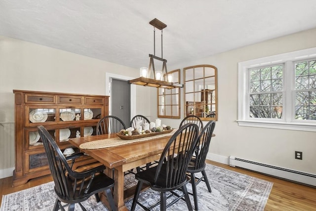 dining area with a baseboard radiator, baseboards, wood finished floors, and a chandelier