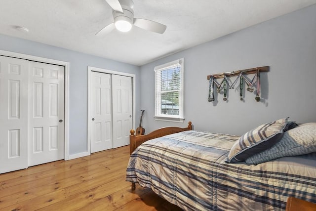 bedroom featuring light wood-style flooring, multiple closets, a ceiling fan, and baseboards