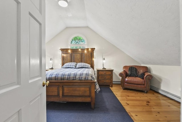 bedroom with baseboard heating, vaulted ceiling, a baseboard heating unit, and wood finished floors