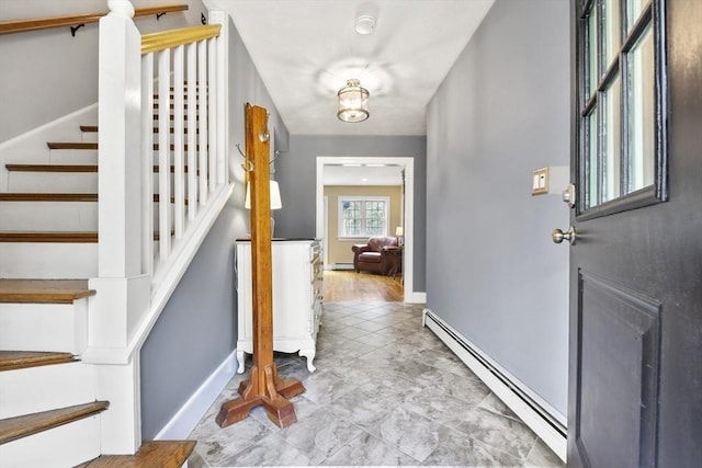 foyer featuring a baseboard heating unit, baseboards, and stairway