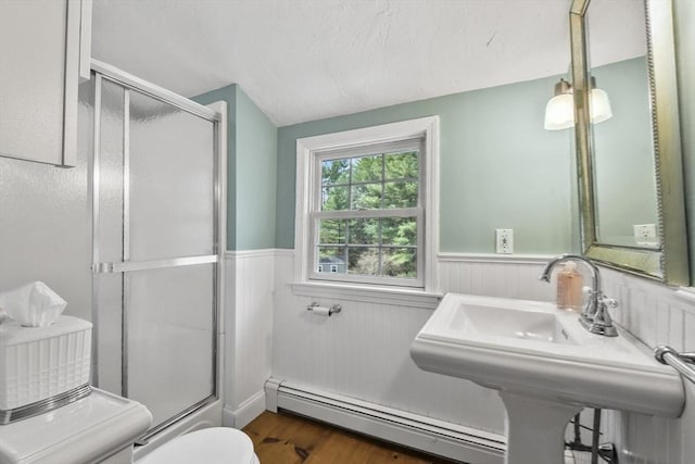 full bath featuring a baseboard radiator, an enclosed shower, toilet, and wainscoting