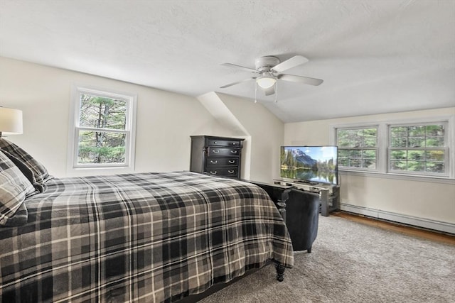 bedroom featuring baseboard heating, ceiling fan, wood finished floors, and multiple windows