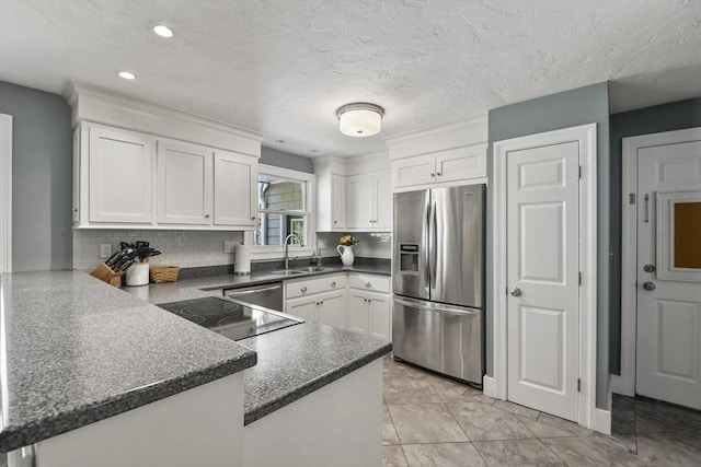 kitchen with a sink, a peninsula, tasteful backsplash, appliances with stainless steel finishes, and white cabinetry