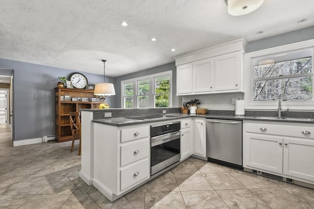 kitchen with white cabinets, stainless steel appliances, a peninsula, a sink, and baseboard heating