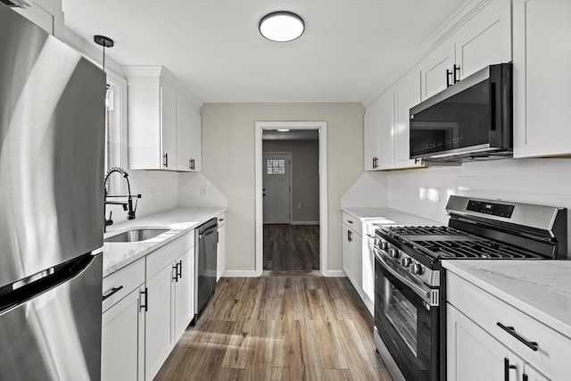 kitchen with white cabinets, hanging light fixtures, sink, and appliances with stainless steel finishes